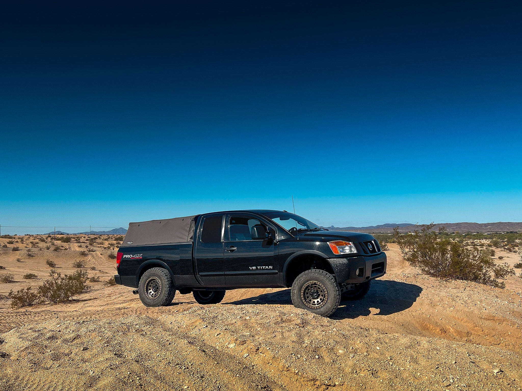 overland sector wheels Nissan Titan Pro 4x lifted on 17x9 satin bronze venture wheels on dirt trail in desert