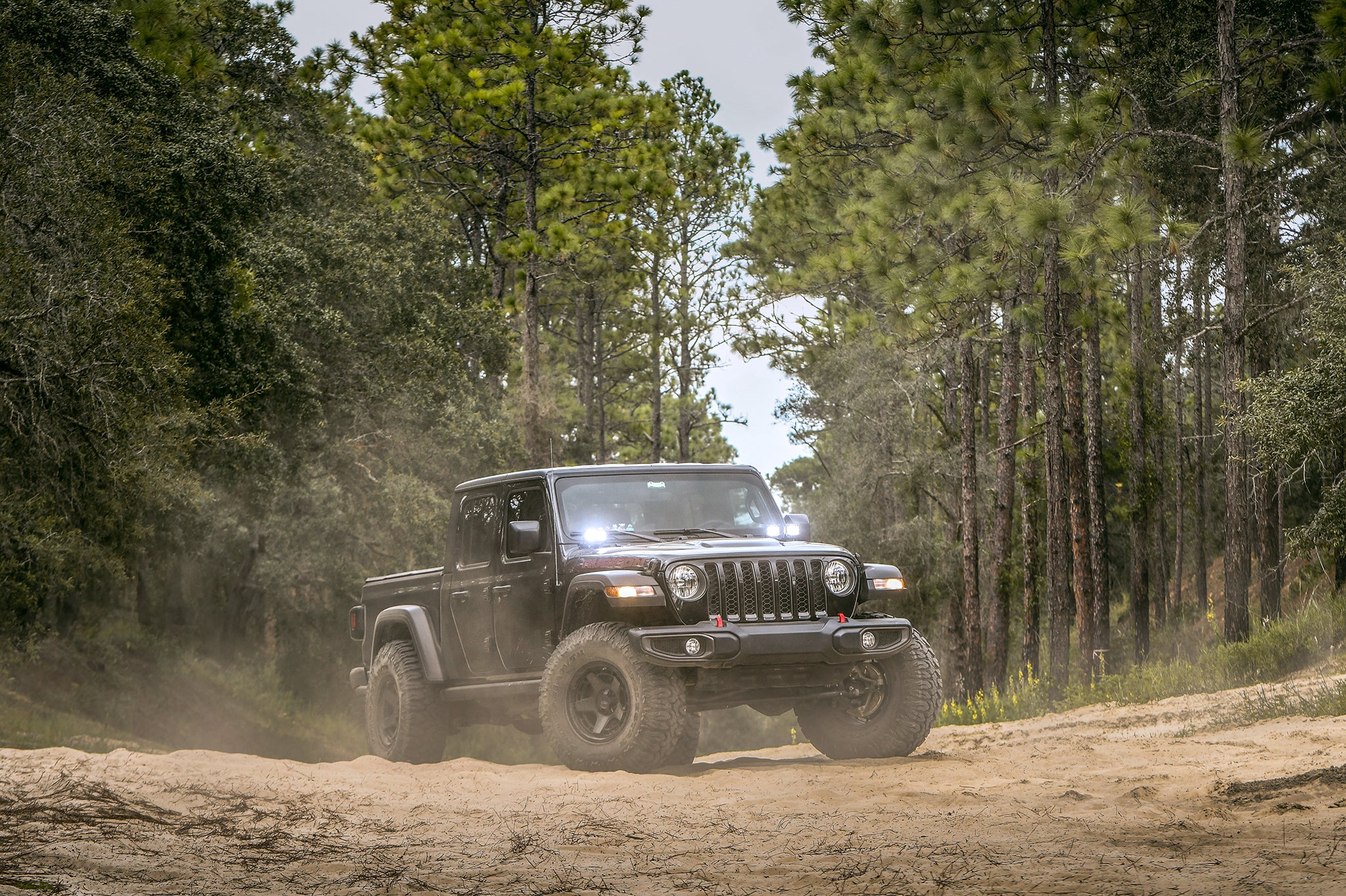 overland sector wheels jeep gladiator rubicon on 17x9 satin black atlas wheels on dirt trail in woods