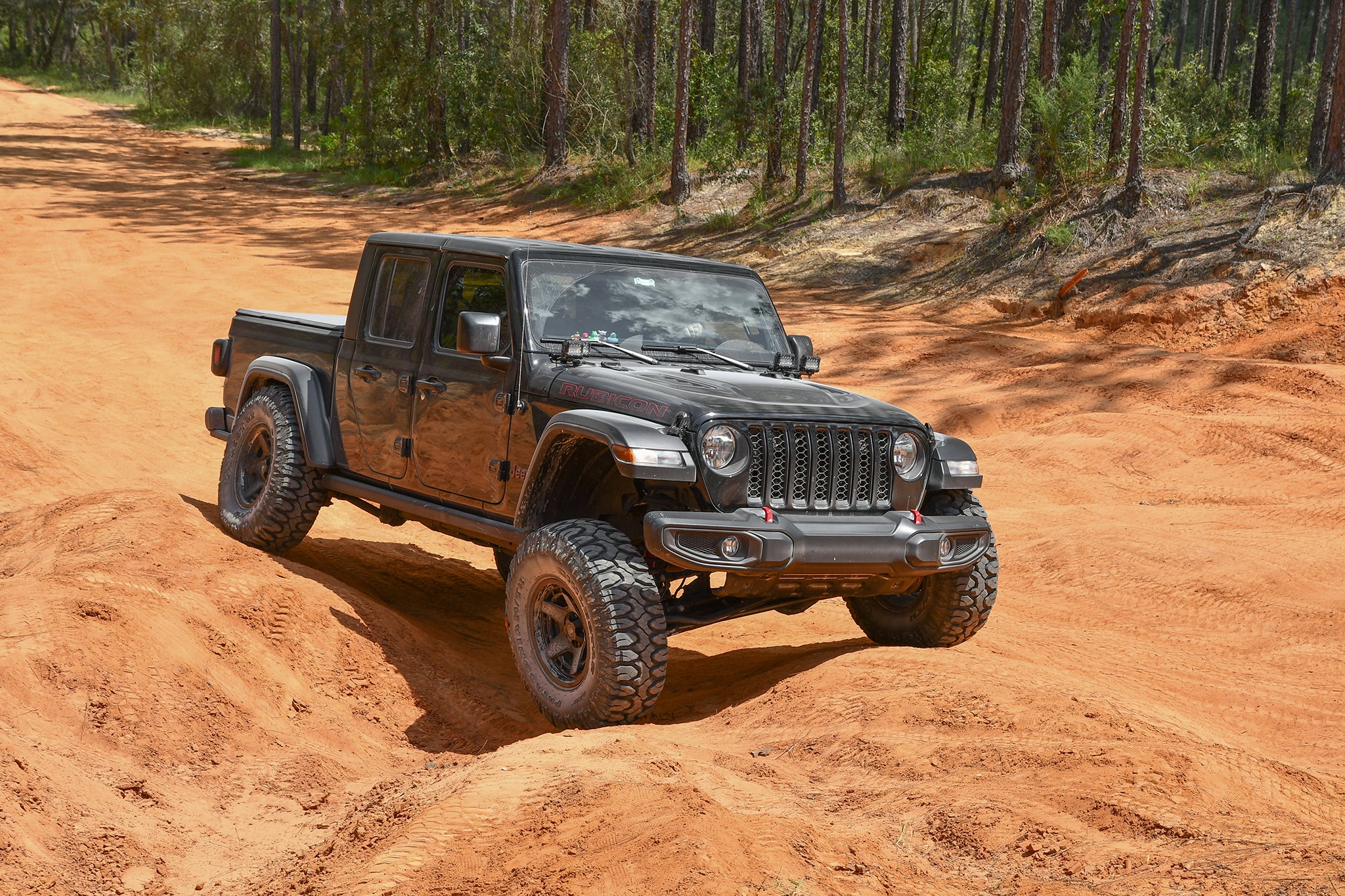 overland sector wheels jeep gladiator rubicon on 17x9 satin black atlas wheels on clay red dirt trail in woods