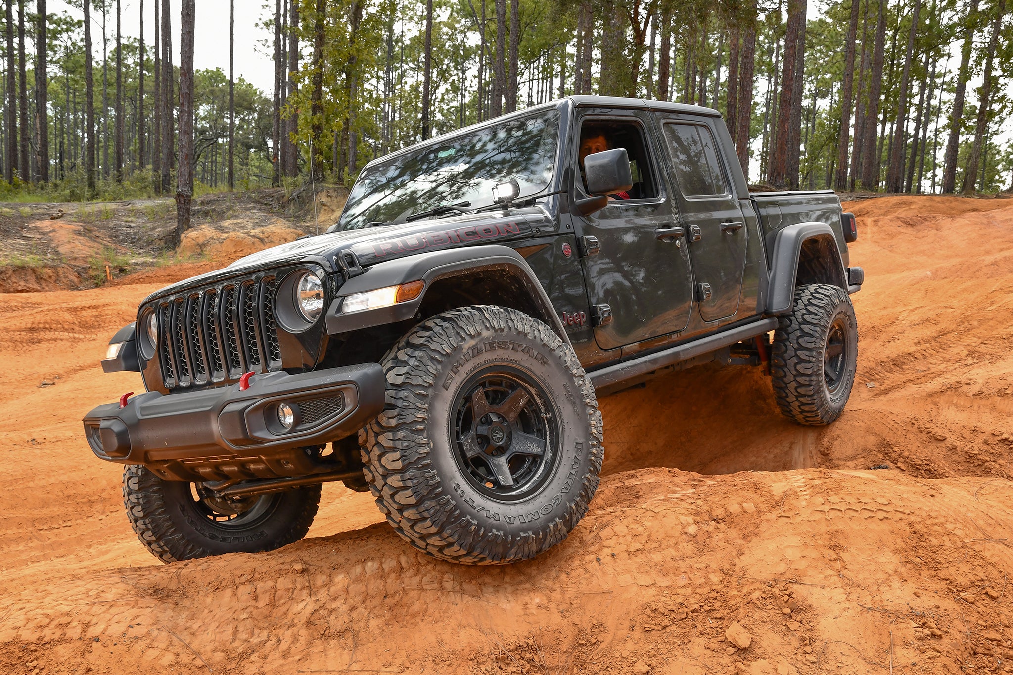 overland sector wheels jeep gladiator rubicon on 17x9 satin black atlas wheels on clay red dirt trail in woods